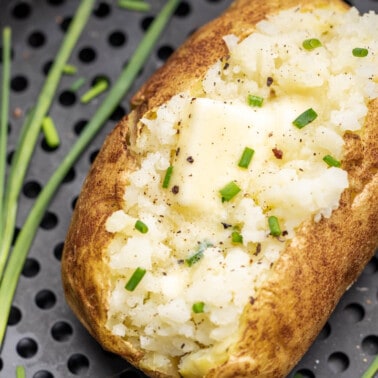 Overhead view looking into an air fryer basket with a baked potato inside.