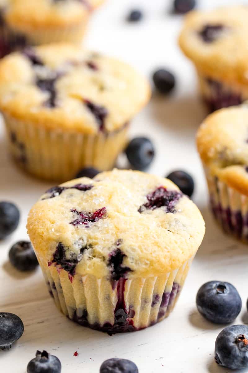 The Best Blueberry Muffins are perfectly sweet, easy to make, and full of blueberry flavor. You'll love this recipe from the world famous original Jordan Marsh department store muffins. Blueberry Muffins and blueberries on a white countertop