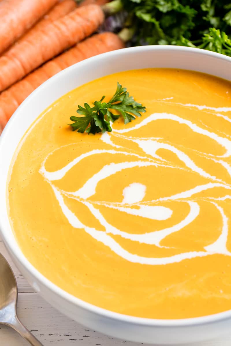 This Carrot Soup is so full of flavor it may very well become your new favorite soup! Who knew carrot soup could be THIS GOOD!?! Carrot Soup in a white bowl.