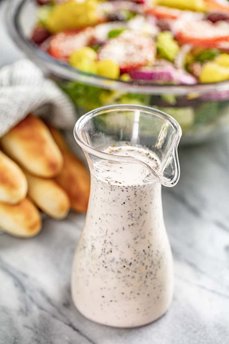 This Copycat Olive Garden Salad Dressing brings that smooth and zesty flavor home to toss into your favorite green salad. Itโs simple and quick to make with nearly universal appeal! Salad Dressing in a small glass pitcher.