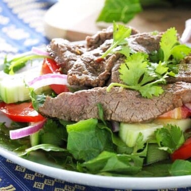 Angled view of Thai Beef Salad served on a white dish and placed on a blue decorative towel.