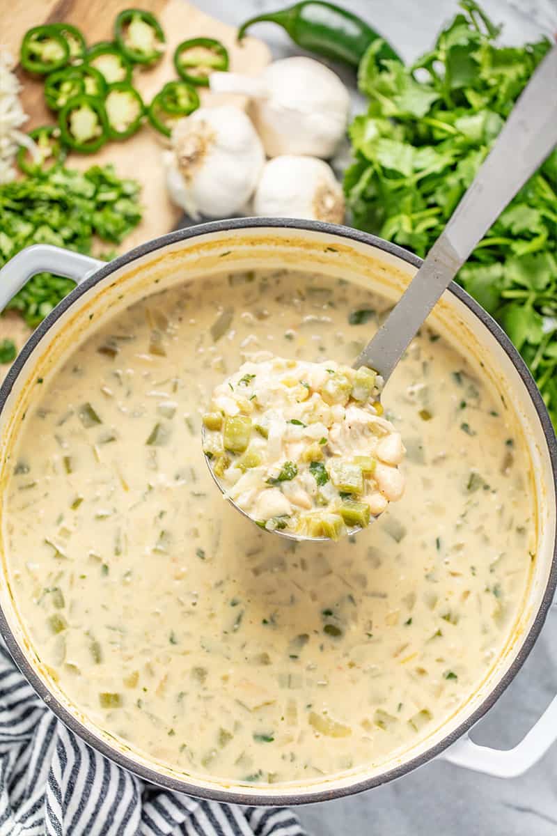 Bird's eye view of White Chicken Chili in a metal ladel above a pot full of white chicken chili.